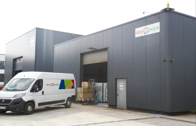 DayBays-Lagergebäude mit Lieferwagen und verpackten Waren auf einer Palette vor dem Hallentor.